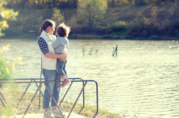 мати і дитина стоять біля красивого озера
 - Фото, зображення