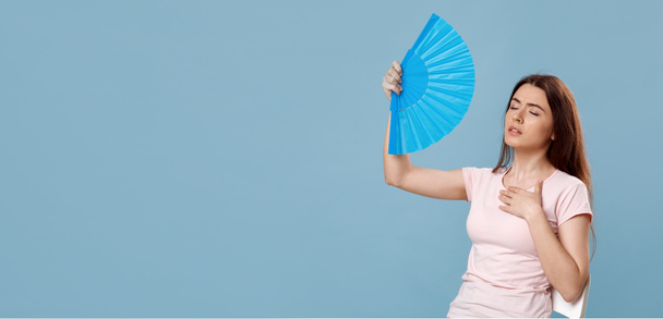 Sweaty beautiful lady with closed eyes cooling with hand fan - Foto, Imagem
