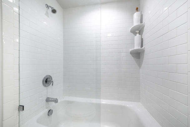 Alcove badkuip met glazen wand divider en een muur met witte tegels - Foto, afbeelding
