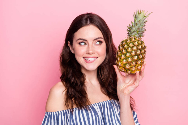 Photo of charming cute young woman dressed striped outfit biting lip holding fruit looking empty space isolated pink color background - Photo, Image