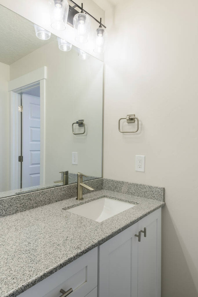 Vanity wastafel van een badkamer met granieten aanrecht en wand gemonteerde verlichting - Foto, afbeelding