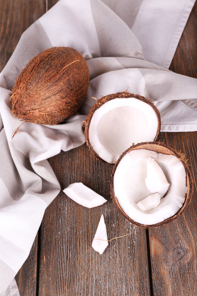 Broken coconut with napkin on wooden background - Fotoğraf, Görsel