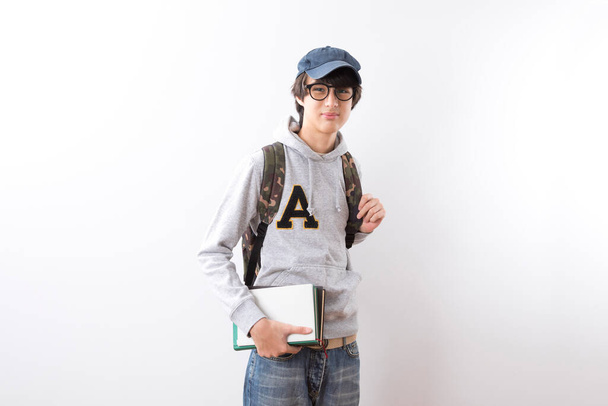 Jóképű tini fiú diákok cipelnek egy hátizsák és könyvek ujjal mutogató álló fehér háttér. - Fotó, kép