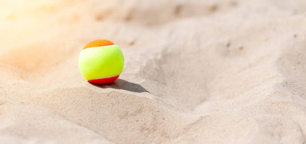 Tennis ball on the sand at the beach close up. Professional sport concept - Photo, Image