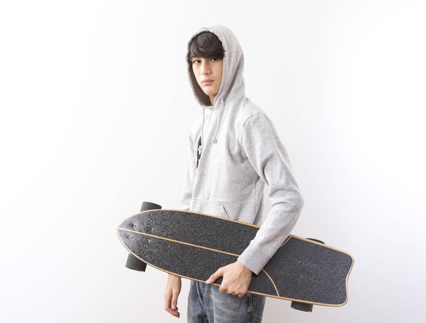 όμορφος έφηβος αγόρι με skateboard σε λευκό φόντο. - Φωτογραφία, εικόνα