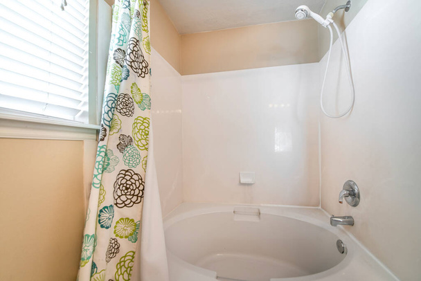 Badkuip en douche combo set in een badkamer met een douchegordijn met bloemen design - Foto, afbeelding