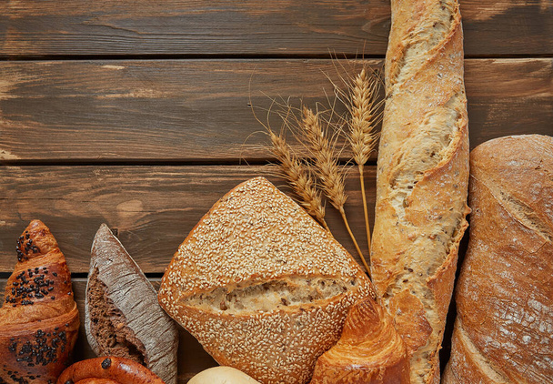 Fresh bread on brown wooden surface and empty space for your text. Top view. - Foto, Bild