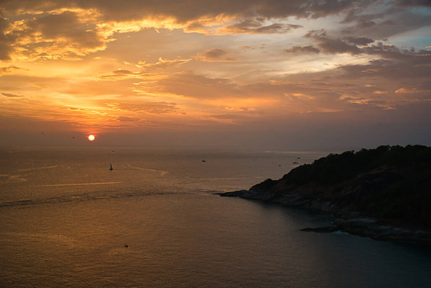 Wunderschöner, atemberaubender Blick auf den goldenen Himmel und die Reflexionen auf dem Andamanenmeer während des Sonnenuntergangs am Wahrzeichen Promthep Cape in Phuket, Thailand - Foto, Bild