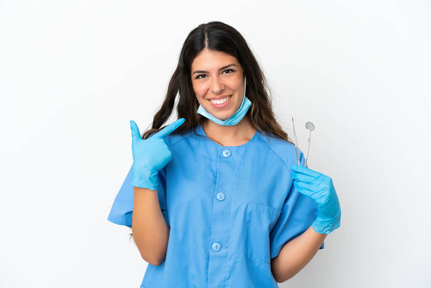 Mujer dentista sosteniendo herramientas sobre fondo blanco aislado dando un gesto hacia arriba pulgares - Foto, Imagen
