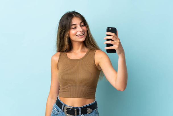 Mladá běloška žena izolované na modrém pozadí dělat selfie - Fotografie, Obrázek