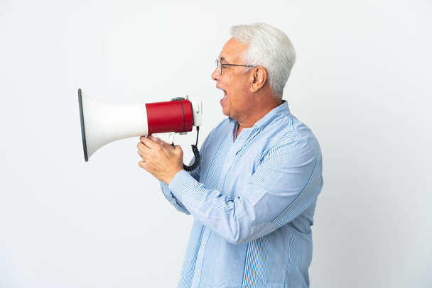 Middle age Brazilian man isolated on white background shouting through a megaphone to announce something in lateral position - Zdjęcie, obraz