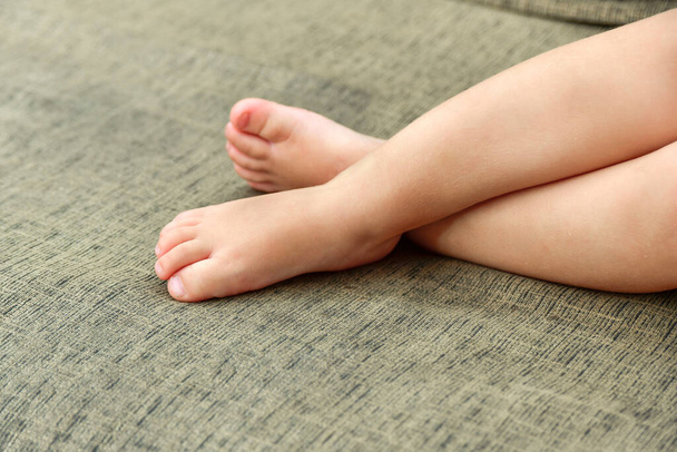 Μικρά πόδια ενός παιδιού ξαπλωμένο στον καναπέ. - Φωτογραφία, εικόνα
