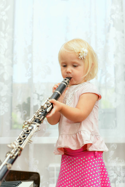 A little girl plays the clarinet. Teaching children music at a music school. - Fotó, kép