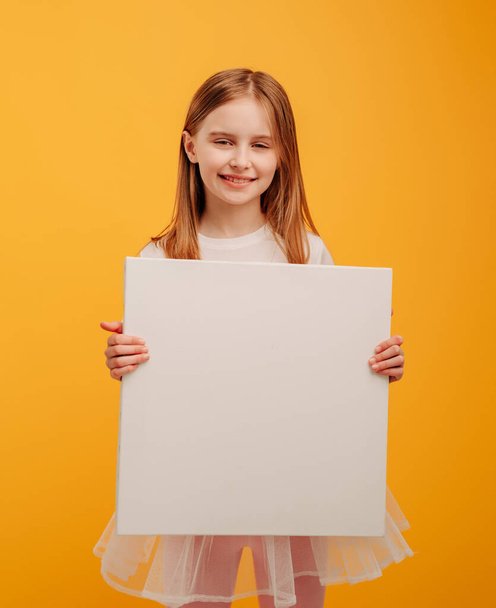 Girl with canvas isolated on yellow background - Фото, изображение
