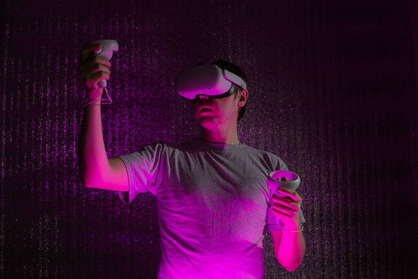 Fiatal fehér férfi 25-30 éves virtuális valóság headset. VR, jövő, kütyü, technológia koncepció neonfényben. - Fotó, kép