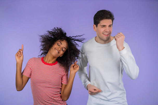 Young african american woman and white man dancing isolated on purple background. Party, happiness, music, Interracial couple concept.  - Photo, image