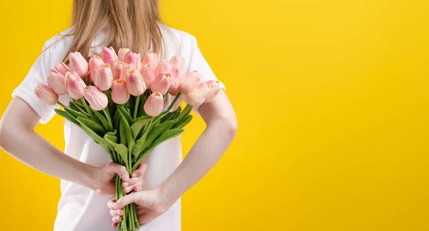 Girl with flowers isolated on yellow background - Photo, image