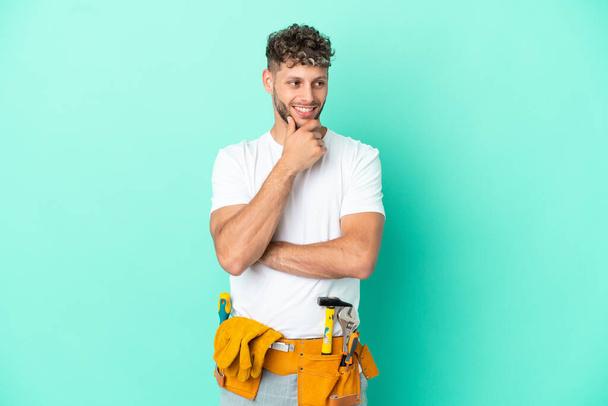 Young electrician blonde man isolated on green background looking to the side - Photo, image
