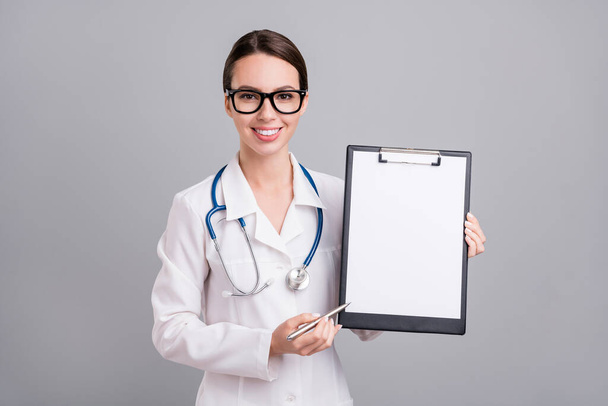 Photo portrait young nurse with sthethoscope smiling keeping pen clipboard isolated grey color background - Zdjęcie, obraz
