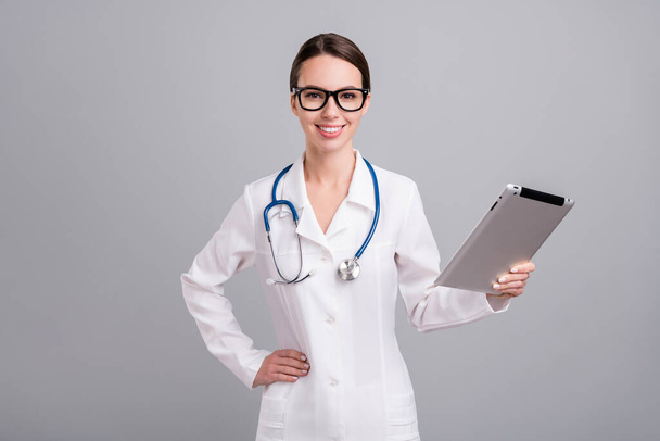 Photo portrait young nurse with sthethoscope smiling using tablet at work isolated grey color background - Photo, Image