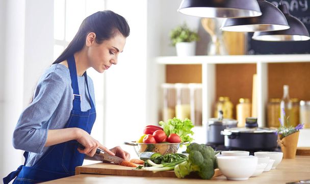 Young woman cutting vegetables in kitchen at home - Photo, image