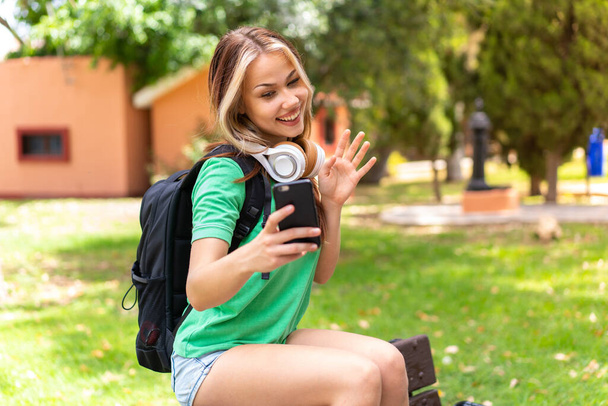 Молода студентка на відкритому повітрі за допомогою мобільного телефону
 - Фото, зображення