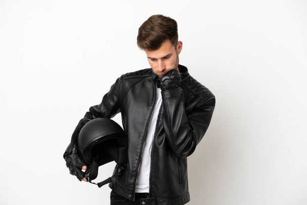 Giovane uomo caucasico con un casco da moto isolato su sfondo bianco avendo dubbi - Foto, immagini