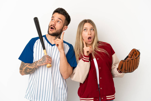 Couple playing baseball over isolated white background thinking an idea pointing the finger up - Photo, Image