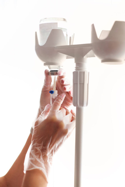 Vrouwelijke arts die de naald uit de fles in de ader van de vrouw steekt tijdens intraveneuze behandeling in de kliniek - Foto, afbeelding