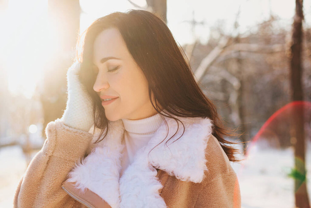 Ottimista giovane donna sorridente mentre si diverte in strada nella soleggiata giornata invernale - Foto, immagini