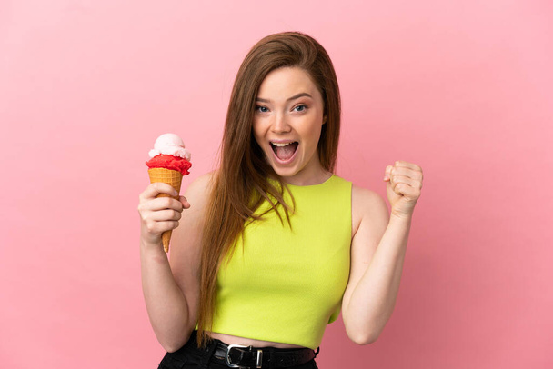 Teini tyttö kanssa cornet jäätelöä yli eristetty vaaleanpunainen tausta juhlii voittoa voittajan asemassa - Valokuva, kuva