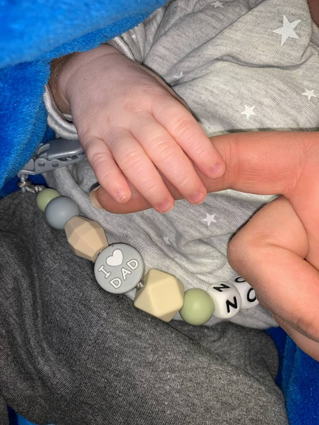The child is holding mom by the finger, close-up. The baby grabbed Mom's hand with his fingers. - Photo, Image