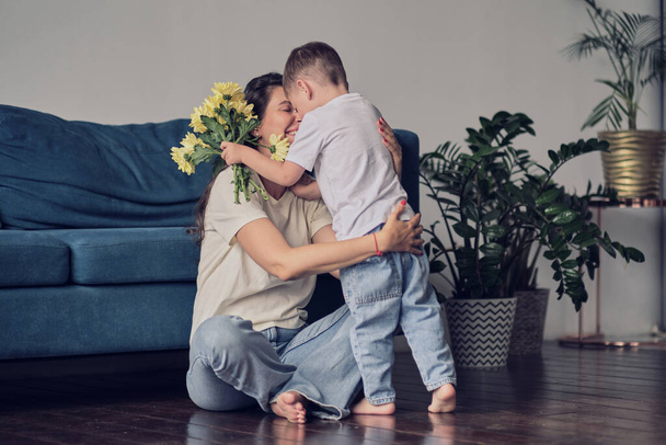 Happy mother day. child son congratulates mother on holiday and gives flowers. congratulating her on mothers day during holiday celebration at home - Φωτογραφία, εικόνα