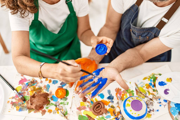 Dois estudantes de meia-idade sorrindo felizes mãos de pintura no estúdio de arte. - Foto, Imagem