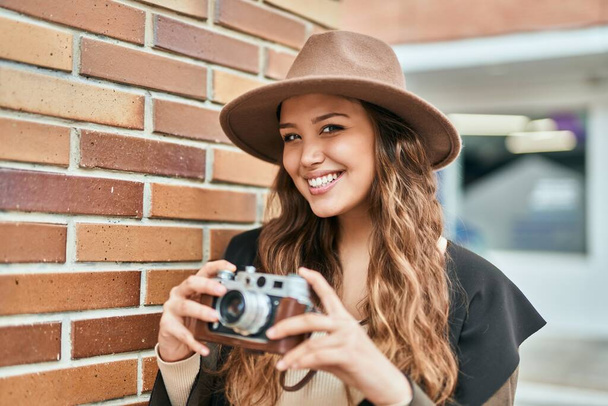 Young hispanic tourist woman smiling happy using vintage camera at the city. - Foto, Bild