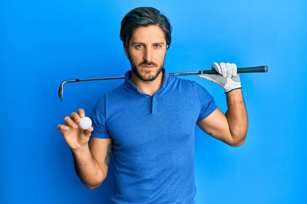 Young hispanic man holding golf ball skeptic and nervous, frowning upset because of problem. negative person.  - Foto, afbeelding