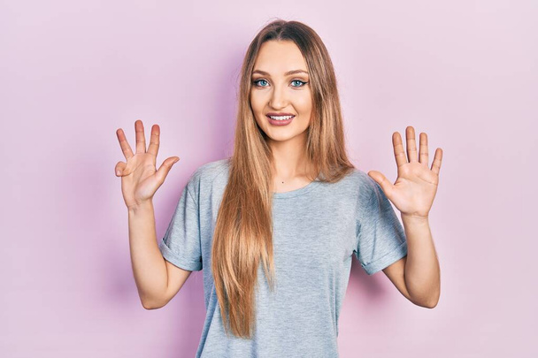 Menina loira jovem vestindo t-shirt casual mostrando e apontando para cima com os dedos número nove, sorrindo confiante e feliz.  - Foto, Imagem