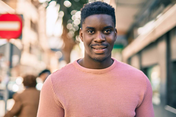 Young african american man smiling happy standing at the city. - 写真・画像