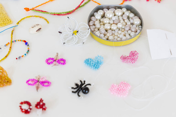 Creative, bright and colorful beads on the white table. Handicraft workplace. Beautiful diy jewelry and calming stress relieving hobby and activity - Zdjęcie, obraz