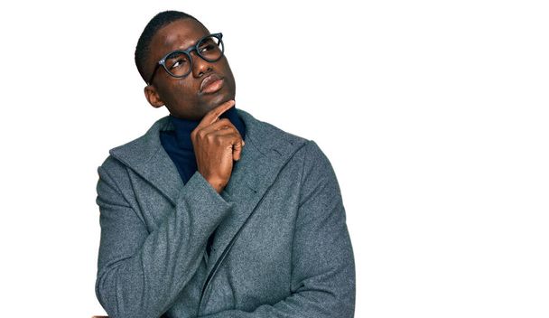若いアフリカ系アメリカ人の男性は、質問、集中的な表現について考えて顎を手でビジネス服や眼鏡をかけています。思慮深い顔で笑顔。疑わしい概念.  - 写真・画像