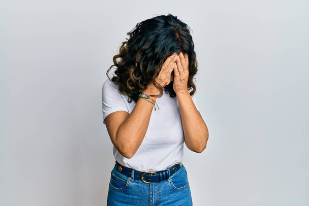 Middle age hispanic woman wearing casual white t shirt with sad expression covering face with hands while crying. depression concept.  - Fotografie, Obrázek