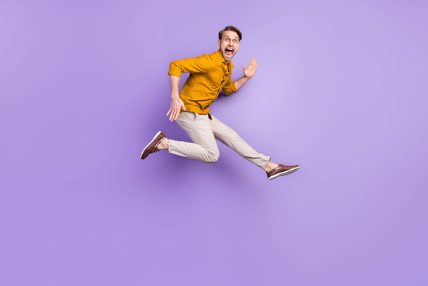 Full length body size view portrait of attractive crazy cheerful guy jumping running isolated over violet purple color background - Foto, afbeelding