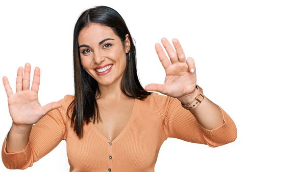 Młoda Latynoska kobieta w luźnych ubraniach pokazuje i wskazuje palcami numer dziewięć, uśmiechając się z uśmiechem pewna siebie i szczęśliwa.  - Zdjęcie, obraz