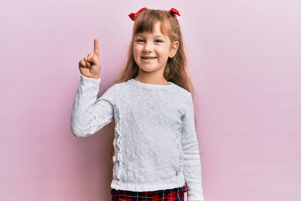 Pieni valkoihoinen tyttö lapsi yllään rento vaatteita hymyillen idea tai kysymys sormella ylös onnellinen kasvot, numero yksi  - Valokuva, kuva