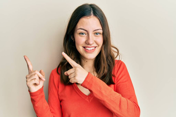 Young brunette woman wearing casual clothes smiling and looking at the camera pointing with two hands and fingers to the side.  - Foto, Imagem
