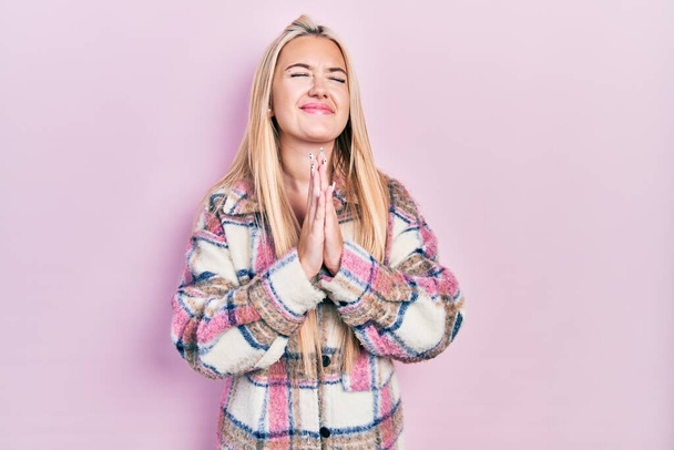 Junge blonde Mädchen in lässiger Kleidung betteln und beten mit den Händen zusammen mit Hoffnung Ausdruck im Gesicht sehr emotional und besorgt. Betteln.  - Foto, Bild