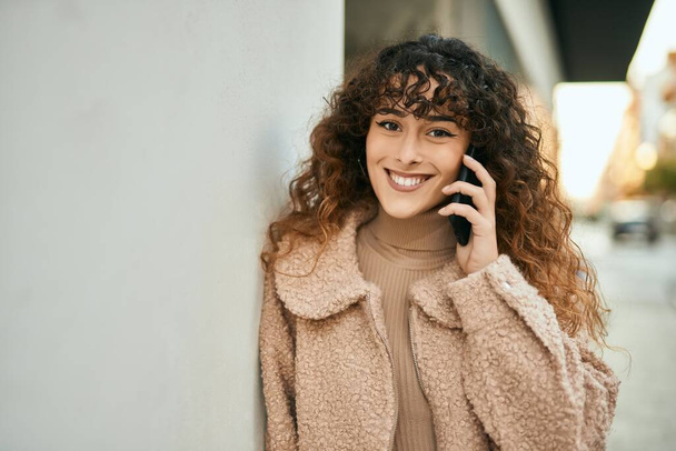 jonge hispanic vrouw glimlachen gelukkig praten op de smartphone in de stad - Foto, afbeelding