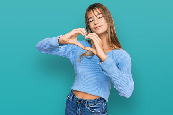 Teenager caucasian girl wearing casual clothes smiling in love doing heart symbol shape with hands. romantic concept.  - Foto, afbeelding