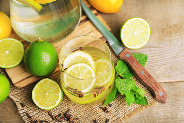 Fresh summer drink with lime and cloves in glass, on color wooden background - Foto, Bild