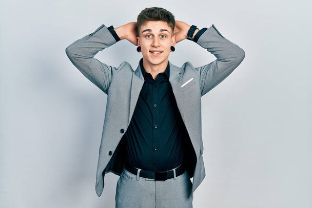 Young caucasian boy with ears dilation wearing business jacket relaxing and stretching, arms and hands behind head and neck smiling happy  - Photo, Image